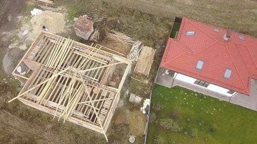 Top Down Aerial View of Two Private Houses One Under Construction with Wooden Roofing Frame and