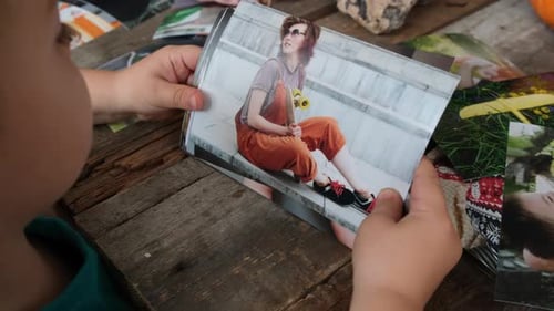 Concepto de impresión fotográfica: niño en edad preescolar mirando fotos impresas de la familia