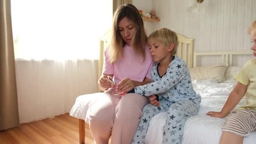 Mother Cuts Son's Nails as Second Child Watches