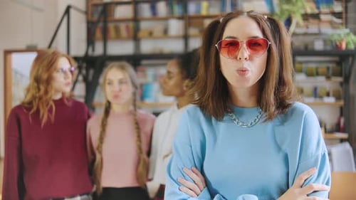 Group of Friends Enjoying a Playful Moment in a Cozy Room While One Blows a Bubble with Gum