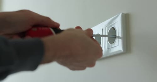 Man Hands of Electrician Dismantling Old Socket Using Screwdriver Replacing Electrical Outlet