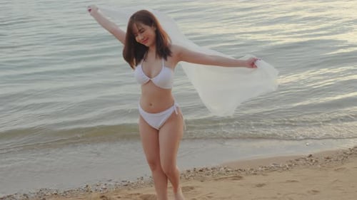 Woman Wear Bikini Swimsuit with Blowing Sarong Enjoying Walking and Spin Body at Beach