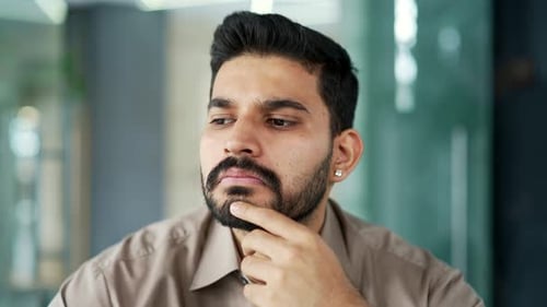 Portrait of a serious thoughtful bearded businessman sitting at workplace in a business office.