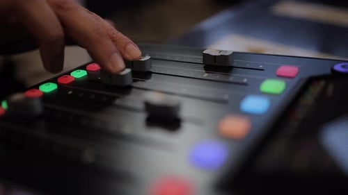 Audio mixer: Fingers slide tracks 2 and 3 faders on sound console