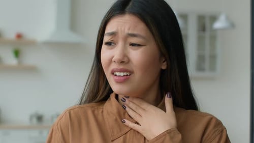 Young Woman with Sore Throat Indoors