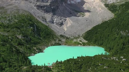 Lake Sorapis bright turqoise water in the Dolomites Italy, pull back aerial