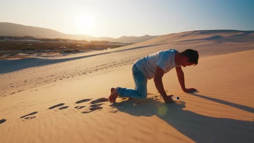 Tired lonely man struggles in the desert with empty bottle of water