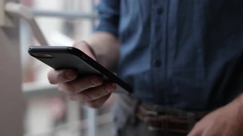 A Smartphone in the Hands of a Man Watches News on the Internet Social Networks Likes Photos Typing