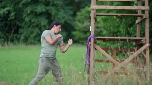 Practicing Martial Arts a Man is Training Outdoors Using a Wooden Post