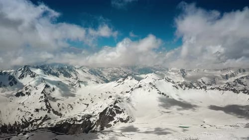 Air flight through mountain clouds over beautiful snow-capped peaks of mountains and glaciers.