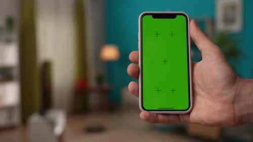 Focus on Man Hand Holding Smartphone with Chroma Key Green Screen for Advertising Area Workspace