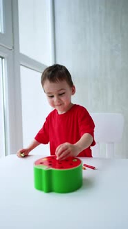 Child Plays with Watermelon Toy at Table Indoors