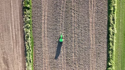 Aerial view of tractor plowing a field at sunset