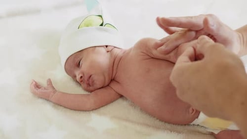 Infant Massage on White Blanket, Soft Lighting