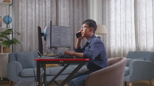 Un jeune programmeur asiatique parle sur un smartphone tout en créant une Appli de développement d'un ingénieur logiciel