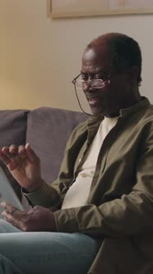 Vertical of Senior Black Man Having Video Chat on Digital Tablet at Home