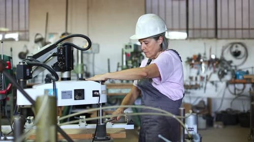 Woman Operating Drill Press in Workshop