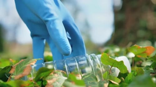 Man at plastic garbage collecting in a polluted park. Rubber gloves, taking a plastic bottle. Slow m