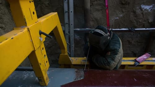 Builder Welds Parts Outdoors. Installation of Piping Under Ground in the Winter