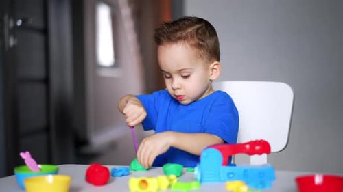 Little Boy Playing with Clay at Table
