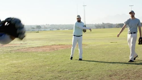 Male catcher stepping, fielding tossed baseball after underhand toss initiating drill on ball field