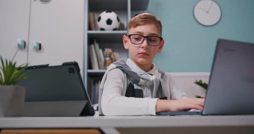 Boy in eyeglasses using tablet computer for online education at home. Distance education online lear