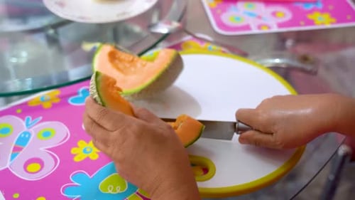 Femme coupant le melon doré en quartiers et en petits morceaux avec un couteau bien aiguisé