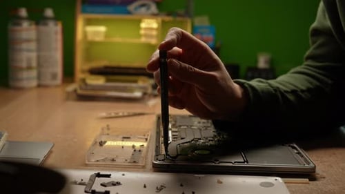Nahaufnahme von der Seite eines erfahrenen Technikers, der die Laptop-Hauptplatine repariert und vorsichtig wieder zusammenbaut