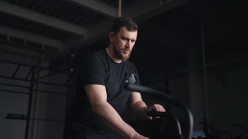 Handsome Bearded Man Doing Exercise On Sport Apparatus In Gym Interval Workout On Stationary Bike