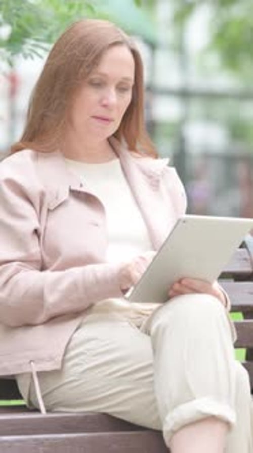 Woman Using a Tablet on Park Bench Outdoors