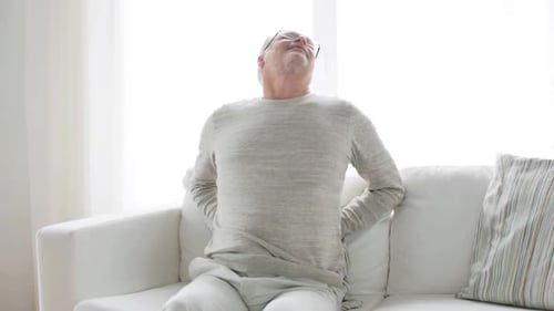 Senior Man Sitting on Couch with Back Pain
