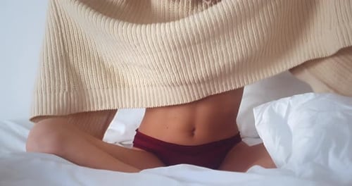 Young Woman Undressing on Bed in Lingerie Young Woman Undressing on Bed in Lingerie