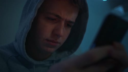 Young Man Using Smartphone Indoors at Night