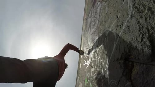 Vista inferior de um jovem grafiteiro pintando com spray colorido sua foto