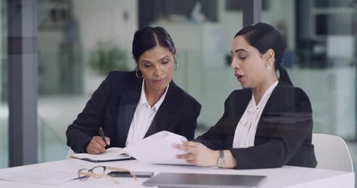 4k video footage of two businesswomen going through paperwork together in an office