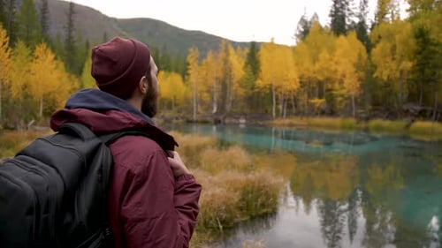 Panoramic View of Adult Backpacker Traveler Male Enjoys Picturesque Lake Viewing
