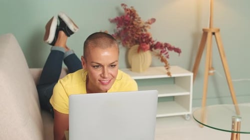 Woman working on laptop computer lying on couch