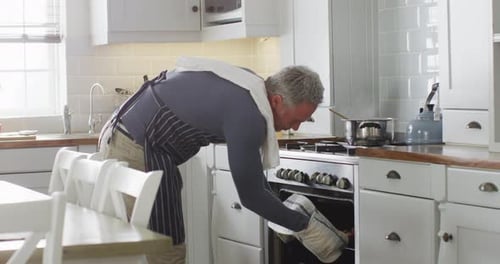 Man Takes Food Out of Oven in Kitchen