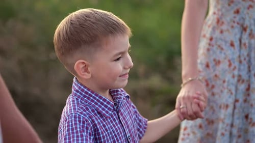 Un garçon d'âge préscolaire heureux passe devant un champ de blé avec ses parents