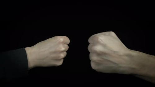Two People Fist Bumping on Black Background