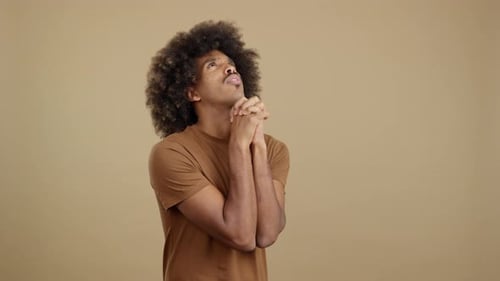 African Man Looking Up While Praying with Folded Hands