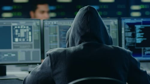 Hooded IT Hacker or Specialist Works on a Personal Computer With Display Showing Software Program w