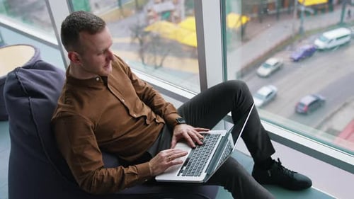 Handsome businessman in office by the window. Young man in brown shirt