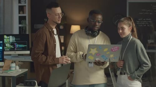 Team von Programmierern schaut auf den Laptop und spricht im Büro