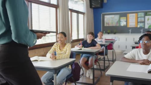 In school classroom, students sitting at desks, listening to teacher attentively
