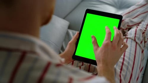 Man Using Tablet with Green Screen at Home