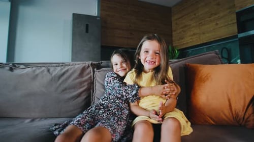 Two Smiling Girls Hugging on the Couch