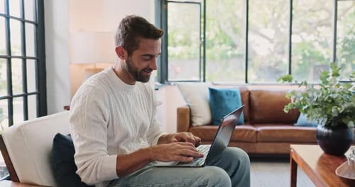 Man Using Laptop on Couch in Modern Home