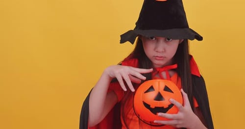 Girl Smiling in Witch Costume with Pumpkin