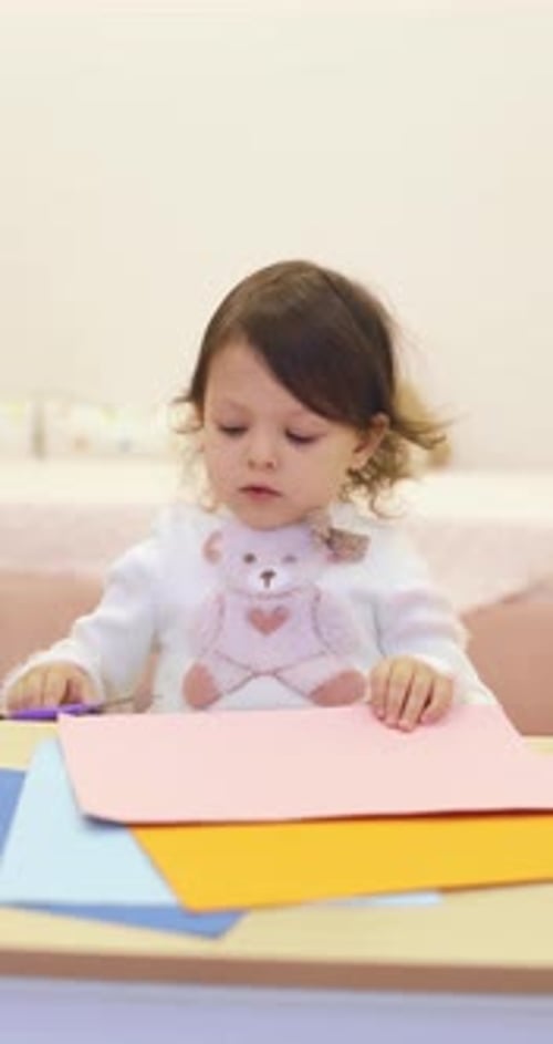 Girl Cutting and Drawing at a Table